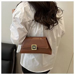 Detailed back view of a brown leather shoulder bag with gold M-logo buckle and chain strap