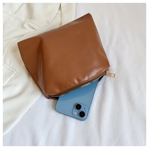 Detail showing the large capacity of the brown leather bag with a smartphone inside