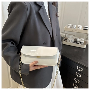 Détail du sac bandoulière en cuir verni blanc brillant avec chaîne dorée élégante et boucle