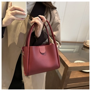 Detail of dark red lychee grain leather bucket bag with matte finish and metal buckle