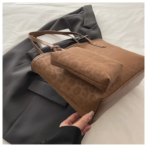 Detail-Set aus braunem Shopper mit Leopardenmuster und Beutel auf grauem Sakko