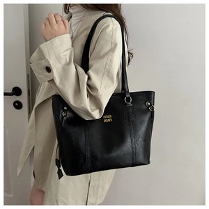 Chic black leather tote bag with gold logo on beige trench coat for office commuting