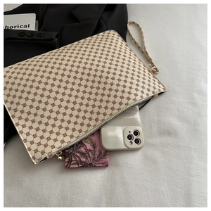Dettaglio della pochette a busta beige con motivi a pois rossi e cinturino da polso chic