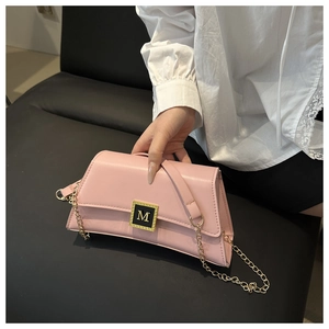 Detail of pink leather handbag with gold M-logo buckle and delicate metal chain strap