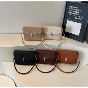 Five minimalist leather shoulder bags in neutral tones displayed on a tiered pedestal