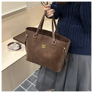 Detailed view of the dark brown leather tote bag with gold hardware and logo finish