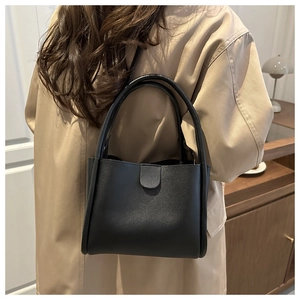 Side view of a vintage black leather bucket bag worn by a model in a warm indoor setting