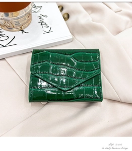 Detail of green crocodile embossed envelope card holder on aesthetic fabric background
