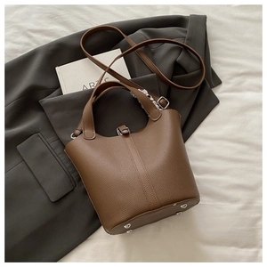 Detail of brown pebbled leather bucket bag with silk scarf handle on blazer