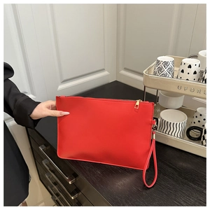 Dettaglio di pochette a busta in ecopelle rossa con cerniera dorata e cinturino