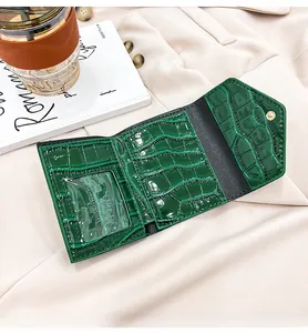 Detail of green croc-embossed tri-fold wallet with transparent ID window and card slots