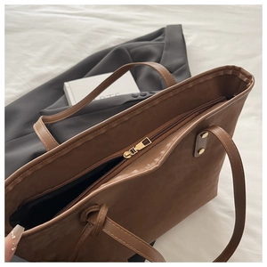 Nahaufnahme des Reißverschlusses und der Metallnieten-Details am braunen Shopper