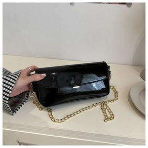 Détails de la surface en cuir verni noir avec chaîne dorée élégante et fermoir métallique