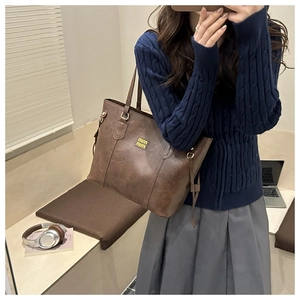 Close-up of vintage dark brown faux leather tote bag with yellow logo on the front