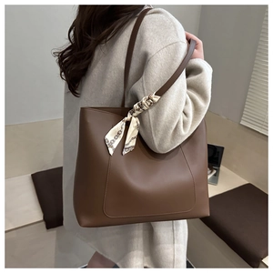 Close-up of brown minimalist tote bag featuring a decorative chain-print silk scarf handle
