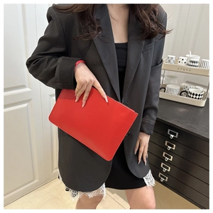 Dettaglio della pochette in finta pelle rosso vivace con cerniera nera minimalista