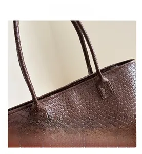 Macro shot of coffee brown tote bag featuring premium woven leather texture and stitching