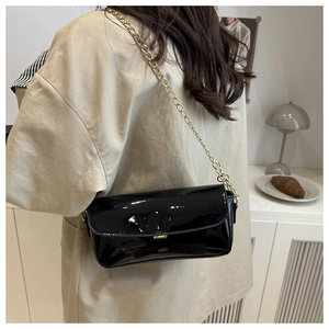 Détail du sac à bandoulière en cuir verni noir brillant avec chaîne dorée et fermoir