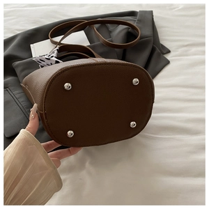 Detailed view of brown bucket bag bottom with silver metal feet and polka dot scarf