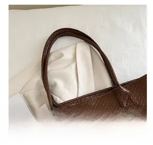 Close-up of the comfortable handle and woven texture on this dark brown tote bag