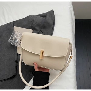 Detail of off-white faux leather handbag featuring a cylindrical gold metal lock and wide strap