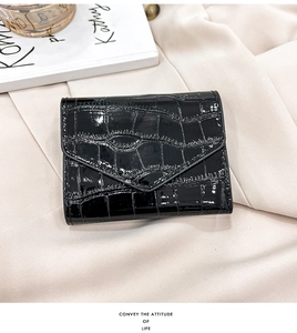 Detail of elegant black crocodile pattern folding wallet on beige fabric background