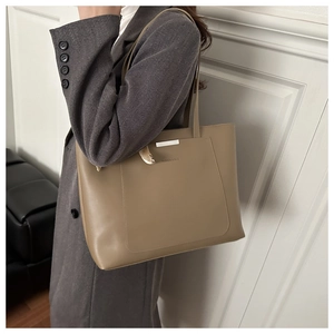 Detail of minimalist khaki tote bag featuring silver hardware and fashion lettering