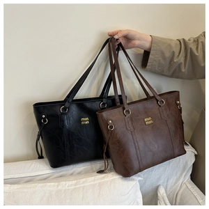Detailed view of the black and brown tote bags showing fine leather texture and metal logo