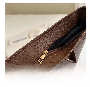 Detail of smooth gold zipper and dark brown woven texture on large commuter tote bag