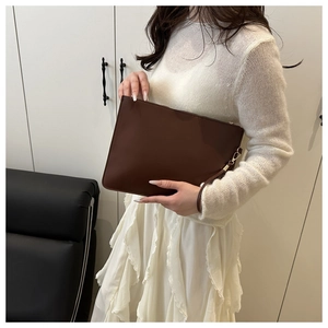 Dettaglio di una pochette minimalista in pelle testa di moro con cerniera dorata