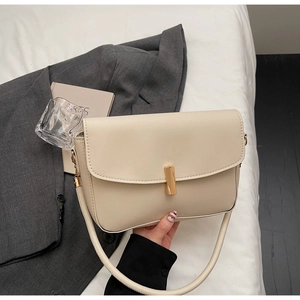 Close-up of cream leather shoulder bag with elegant gold metal lock and wide strap