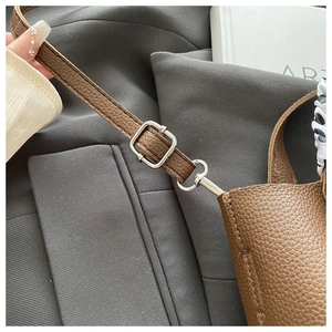 Detail of brown litchi pattern leather shoulder bag with silver adjustable buckle strap
