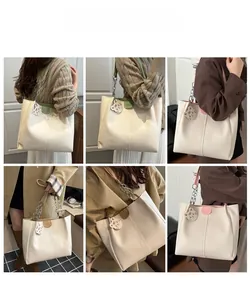 Detail view of large tote bag with chain strap and cat charm shown on model