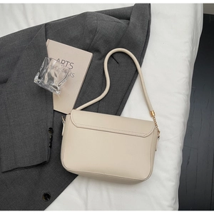 Detail of the stitching and golden hardware on a cream leather underarm bag