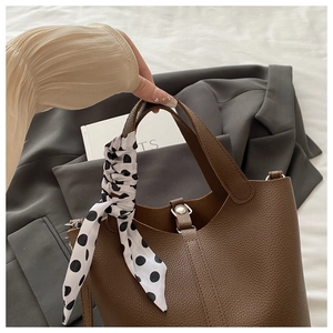 Detail of dark brown leather bucket bag with decorative polka dot silk scarf handle