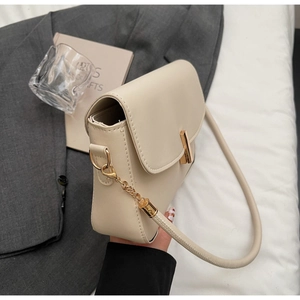 Detail of cream white leather shoulder bag featuring gold buckle and chain strap