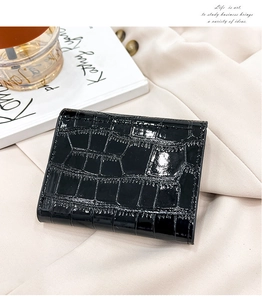 Close-up of black crocodile pattern patent leather card holder on soft beige fabric