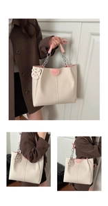 Detail of soft beige tote bag with pink leather trim and cartoon tiger pendant