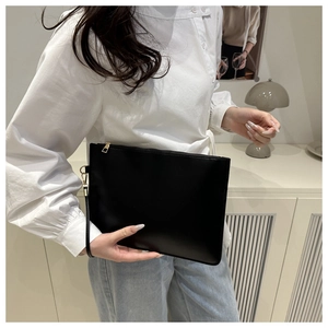 Dettaglio di una pochette nera in similpelle con cerniera dorata e cinturino da polso