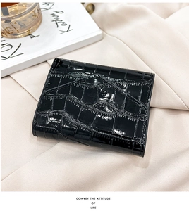 Detail of glossy black crocodile pattern card holder with premium stitching on textured fabric