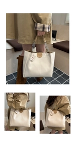 Detail of cream white tote bag with leather logo patch and metal chain strap accent