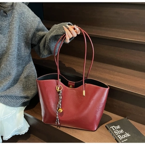 Detail of burgundy tote bag with wave-edge rim and creative beaded tassel on wooden stairs