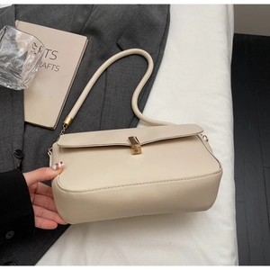 Detail view of cream leather shoulder bag with elegant gold metal buckle and flap closure