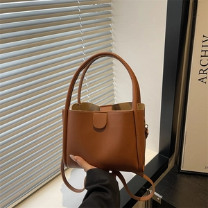 Minimalist brown faux leather bucket tote bag with top handles and adjustable strap