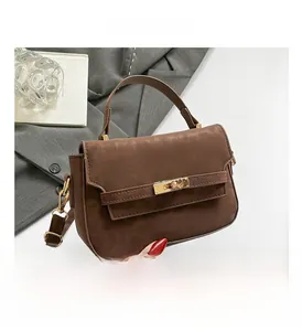 Detail of a brown faux suede handbag with a gold twist lock and single handle