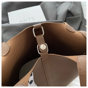 Close-up of brown litchi grain leather tote bag with silver metal buckle and strap