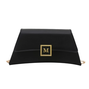 Elegant black matte trapezoid shoulder bag with gold M-logo hardware and metal chain strap