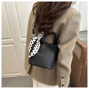 Detail of black lychee grain leather bucket bag with a stylish polka dot scarf on the handle