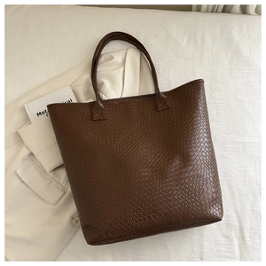 Detailed macro view of deep brown woven texture on large capacity faux leather tote bag