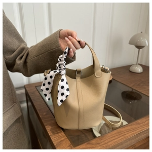 Gros plan du sac seau en cuir kaki avec foulard en soie à pois et texture élégante